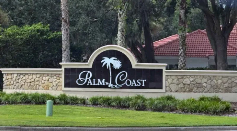 Palm Coast, Florida city welcome sign with tile-roofed homes behind it